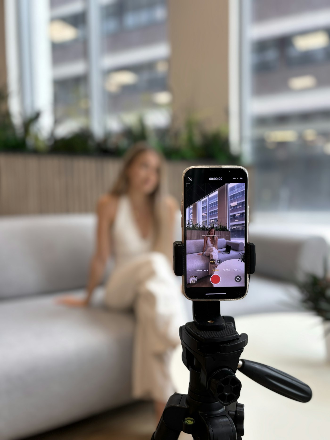 三脚に立てたスマートフォンで、ソファに座って話す様子を撮影している